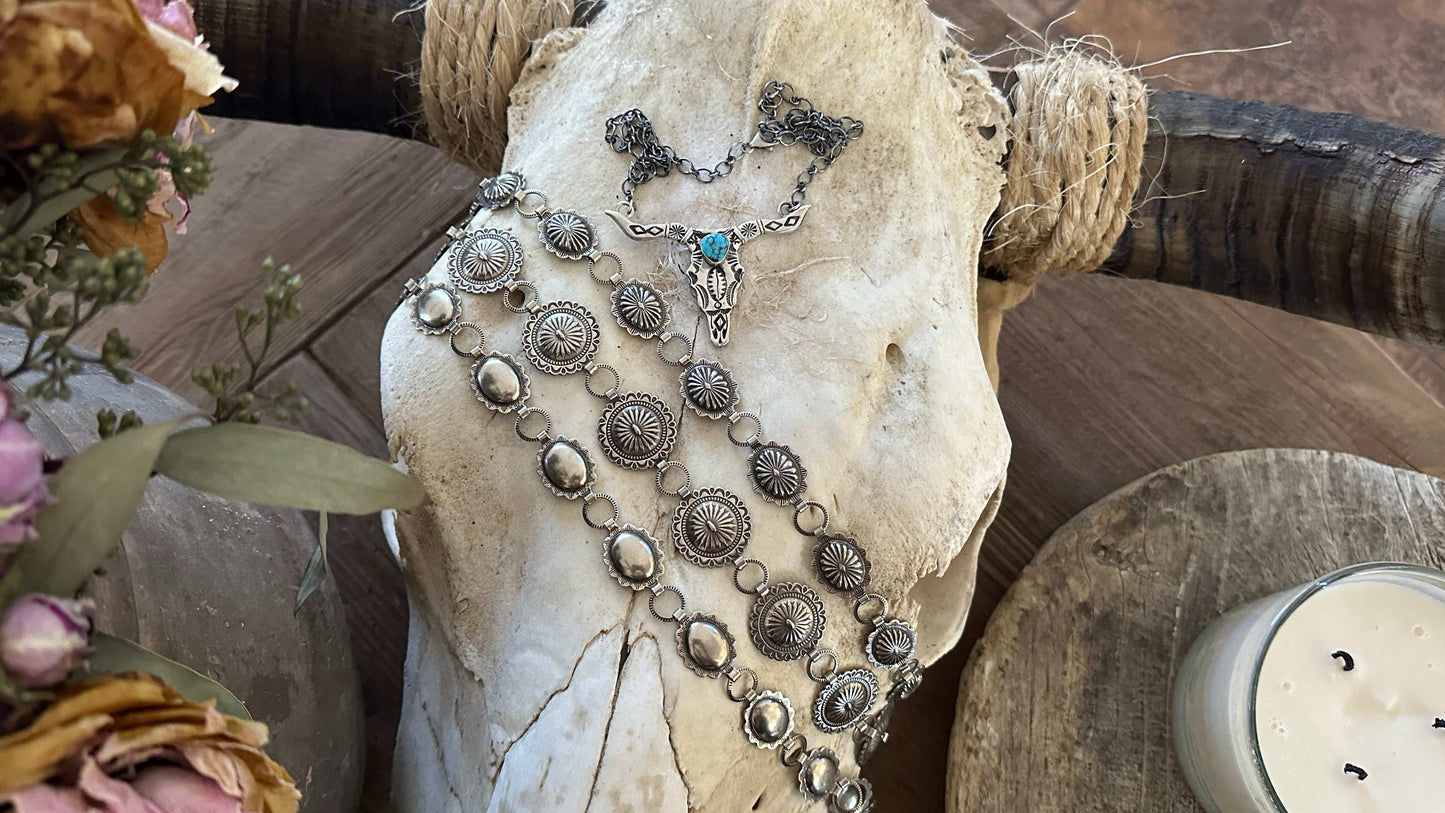 Nickel silver concho belts draped over a cow skull as coffee table decor