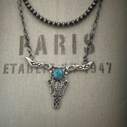 Sterling silver cow skull necklace with genuine turquoise on dress form