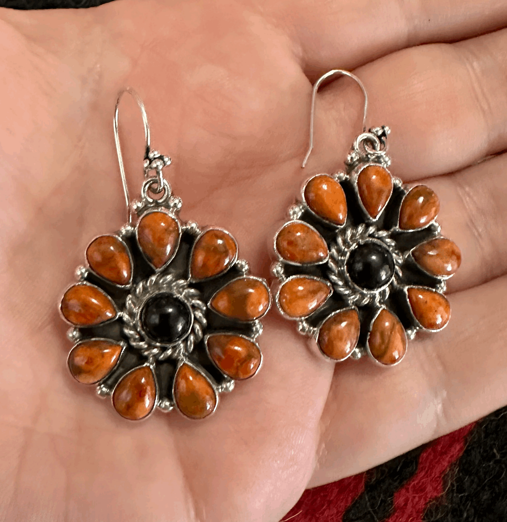 Sterling silver earrings that feature a ring of teardrop shaped orange Mojave stones around a beautiful round onyx stone. These earrings feature a sterling silver hook ear wire.